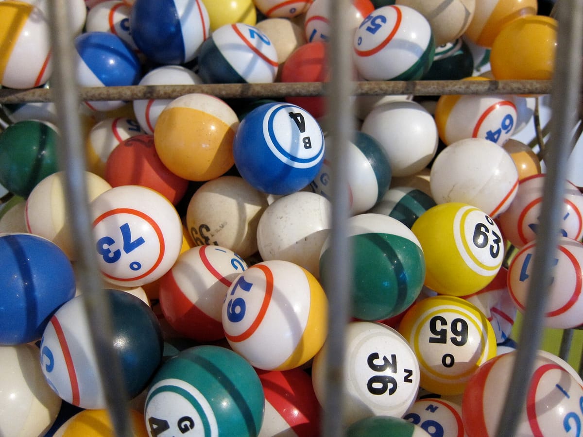 Coloured American bingo balls marked with letters and numbers, such as B4, N36 and O65, inside a wire cage