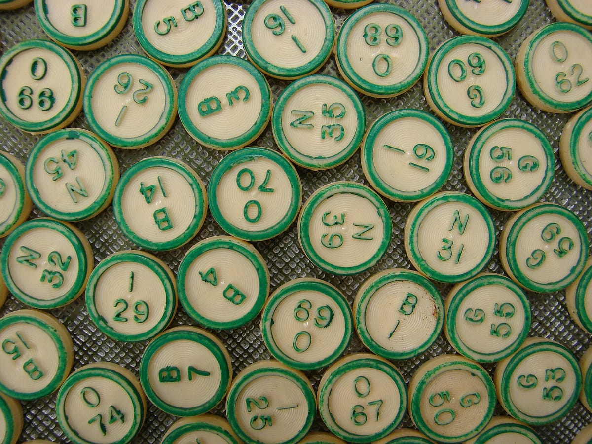 A heap of old round bingo counters with green rims, each printed with a letter and a number