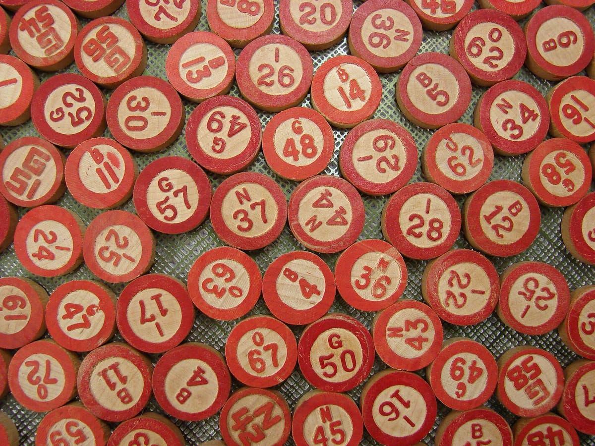 A heap of old round bingo counters with red rims, each printed with a letter and a number