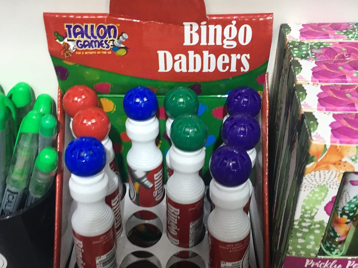 A shop display box of bingo dabbers with red, blue, green and purple caps