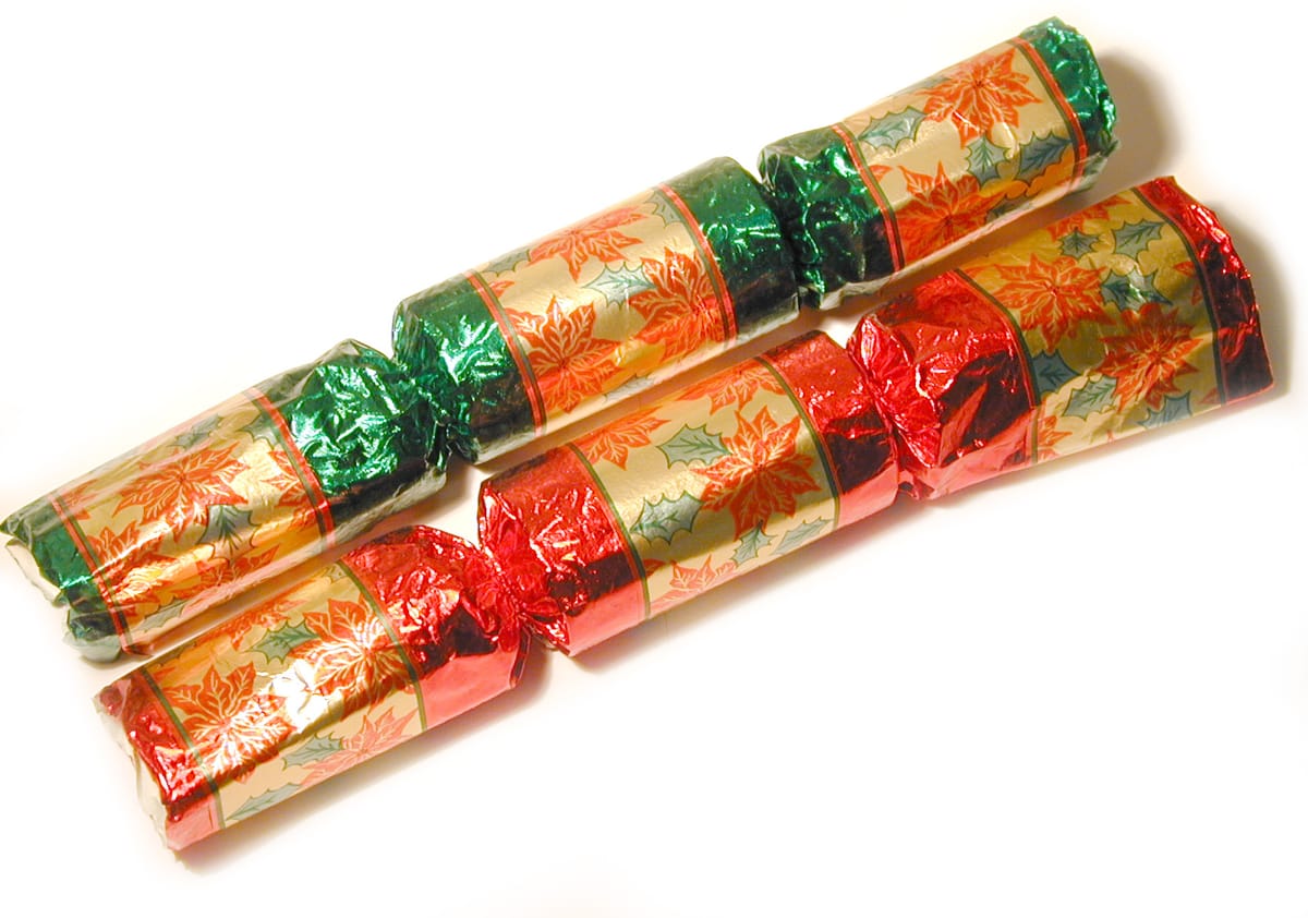 Two Christmas crackers in red, green and gold foil on a white background